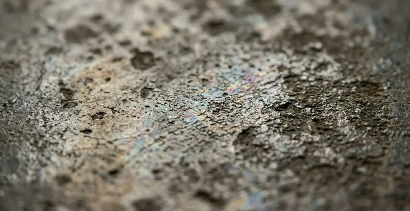 Vue macro d'un sol industriel montrant la formation invisible de biofilm due au surdosage de détergent