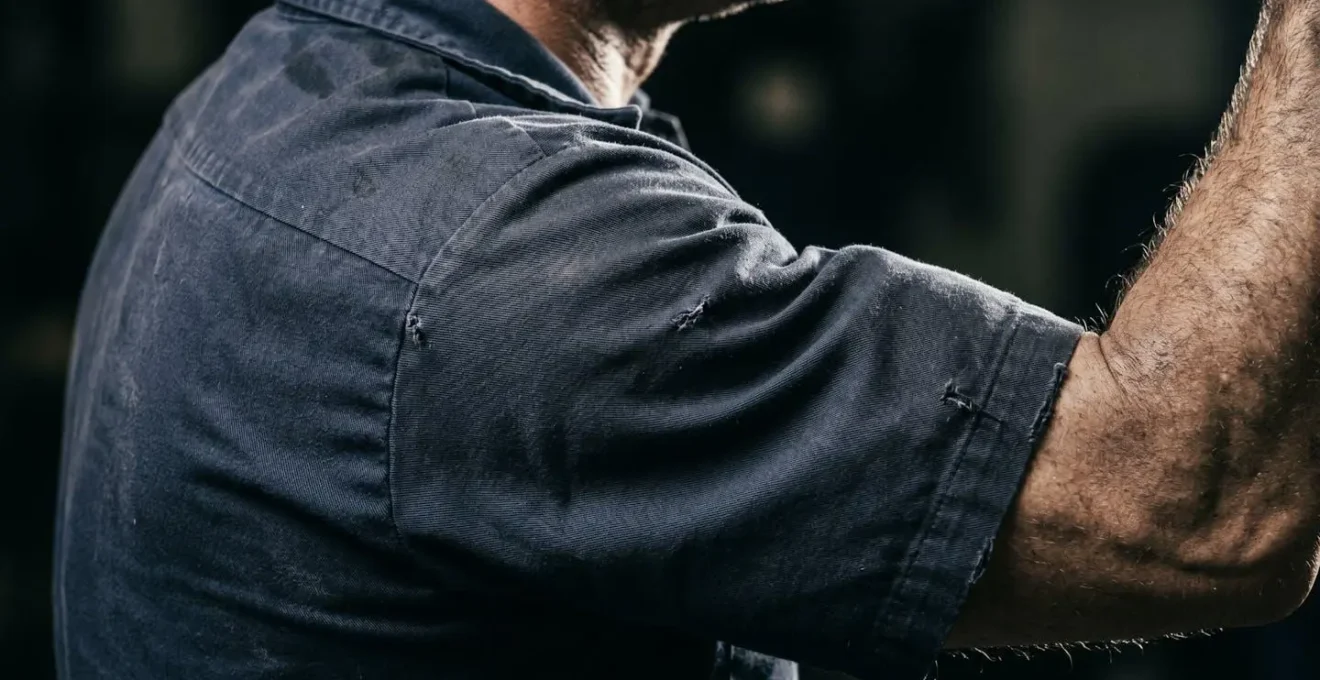 Opérateur industriel montrant des signes de fatigue après travail bras levés